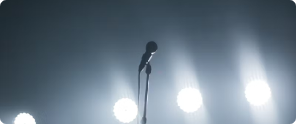 Microphone on a stand illuminated by stage lights, symbolizing the importance of storytelling and captivating presentations in finance.